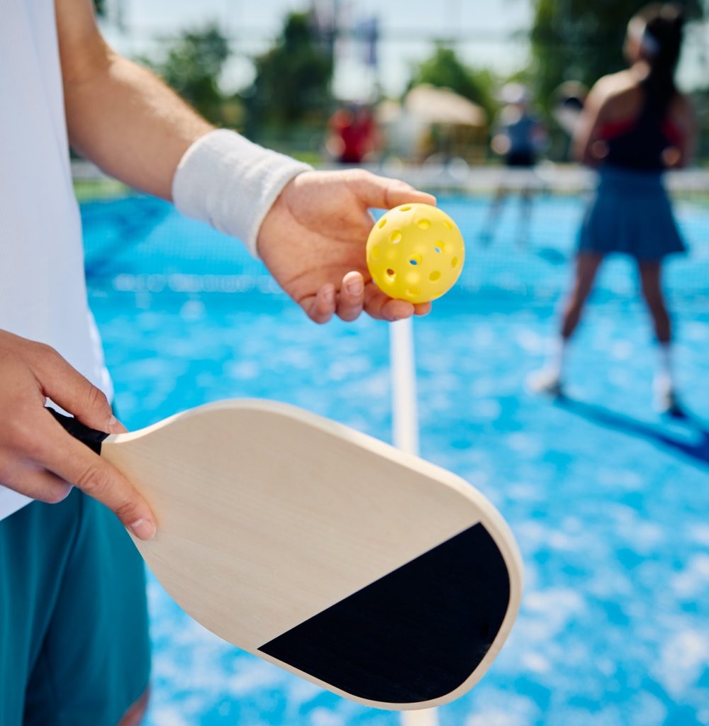 Close up of man serving the ball while playing mixed doubles in pickleball. Close up of man serving the ball while playing mixed doubles in pickleball.