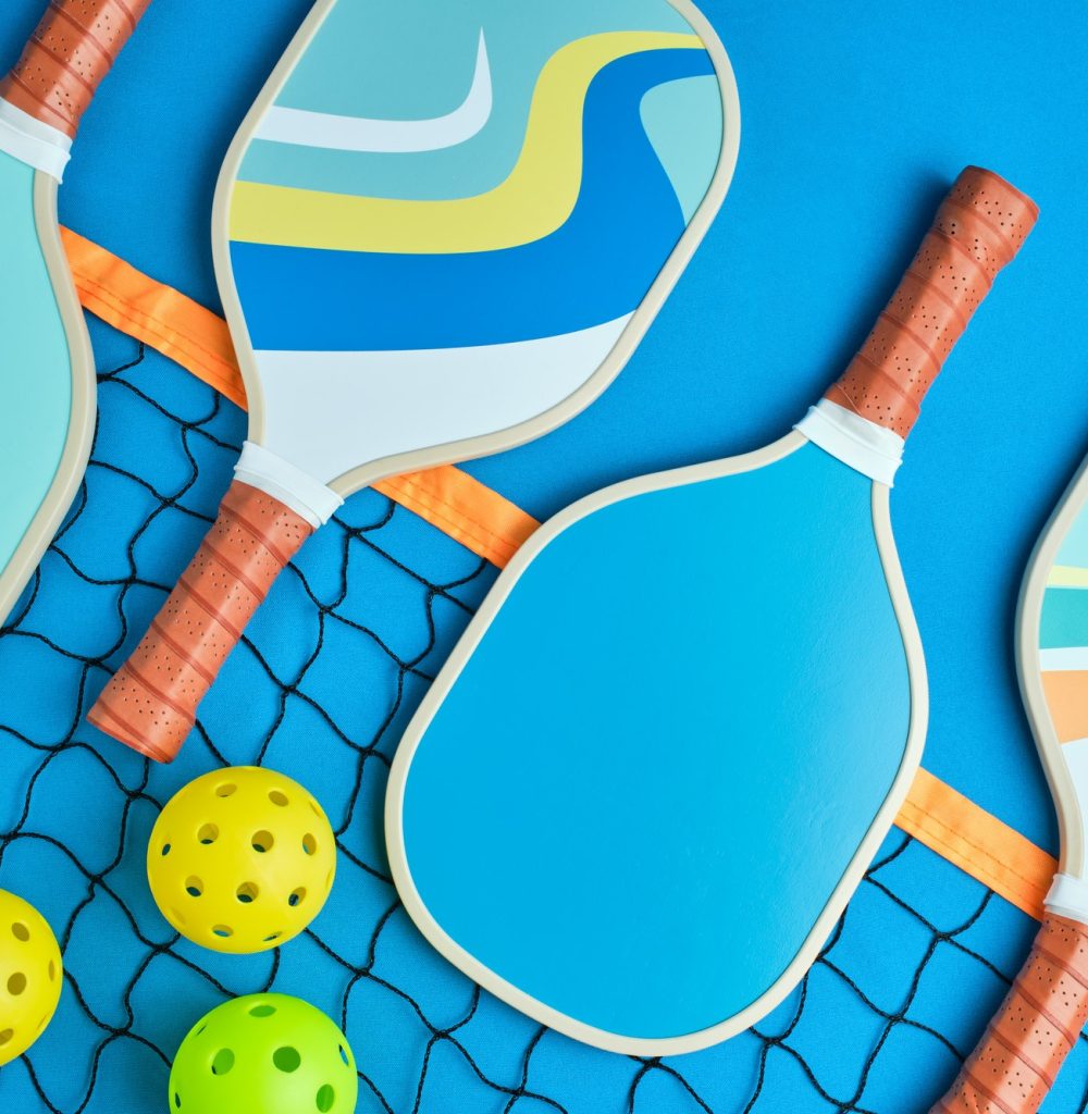 pickleball paddles in blue tones on top of a net on a blue background with three balls next to it pickleball paddles in blue tones on top of a net on a blue background with three balls next to it